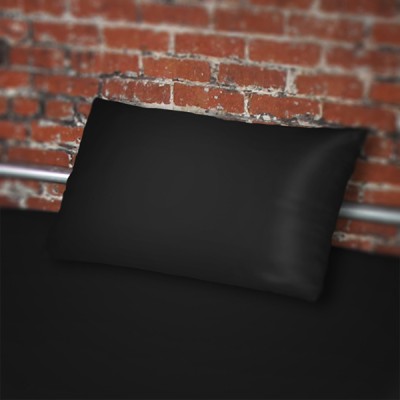 Black pillowcase on black fluidproof sheet against a brick wall