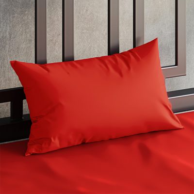 Close up of a Sheets of San Francisco Red waterproof pillow case on a bed covered in a Red Sheets of San Francisco fluidproof fitted sheet and against a black metal bedhead with the polished concrete wall behind showing through.
