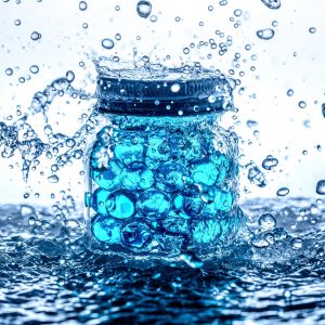 Warming a cooling gels image of a glass jar filled with bright pale blue gel balls and surrounded by splashing water