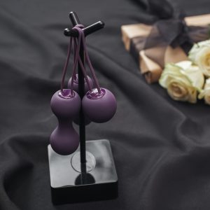 Purple Kegel Balls on a black metal stand on a backdrop of a black fuidproof sheet